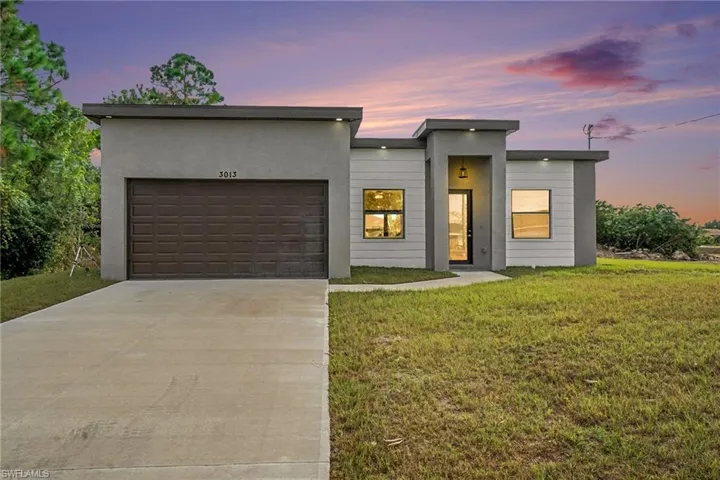 Contemporary house with concrete driveway, a garage, a yard, and stucco siding