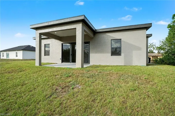 Rear view of house featuring a lawn, a patio area, and stucco siding