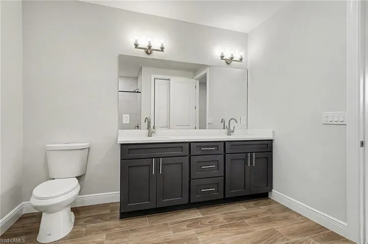 Full bath with wood tiled floors, double vanity, and a stall shower