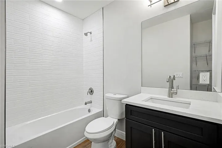 Bathroom featuring vanity, bathtub / shower combination, and dark wood finished floors