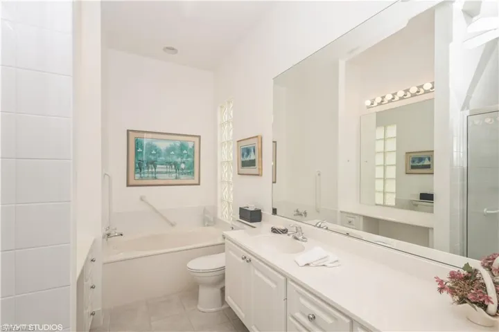 Bathroom featuring a bathtub, tile flooring, oversized vanity, and toilet