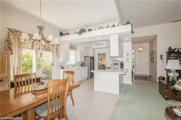 Carpeted dining room featuring sink and ceiling fan with notable chandelier