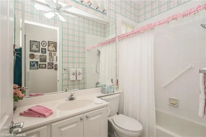 Full bathroom with toilet, shower / bath combo, ceiling fan, and oversized vanity