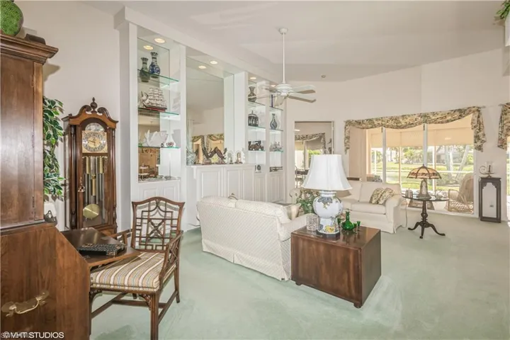 Carpeted living room with high vaulted ceiling and ceiling fan