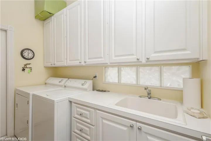 Laundry room featuring separate washer and dryer, sink, and cabinets