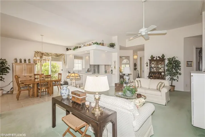 Living room featuring light carpet and ceiling fan with notable chandelier