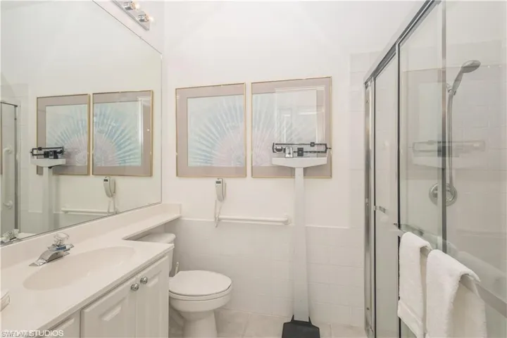 Bathroom with tile walls, walk in shower, tile floors, toilet, and vanity