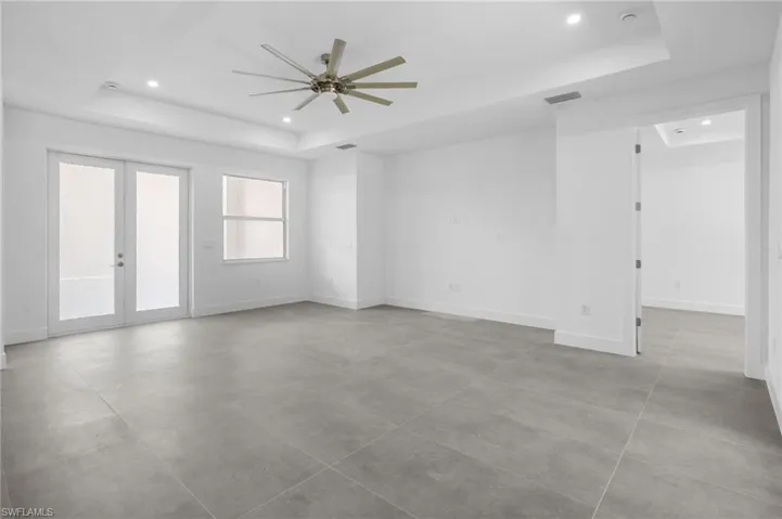 Empty room featuring a tray ceiling, french doors, ceiling fan, and recessed lighting