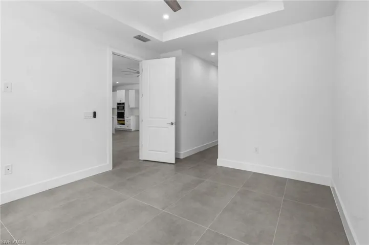 Unfurnished bedroom with light tile patterned floors, a tray ceiling, a ceiling fan, and recessed lighting