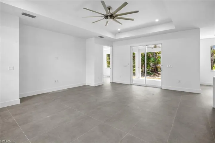 Unfurnished room featuring a raised ceiling, recessed lighting, ceiling fan, and tile patterned flooring