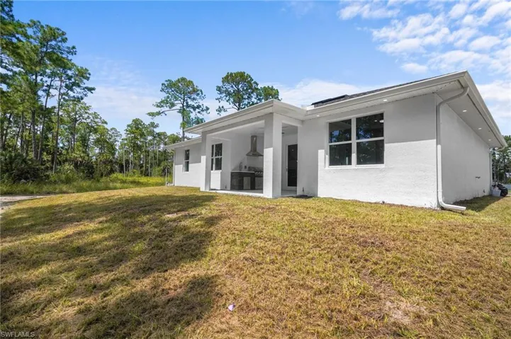 Rear view of property featuring a patio area, a yard, and stucco siding