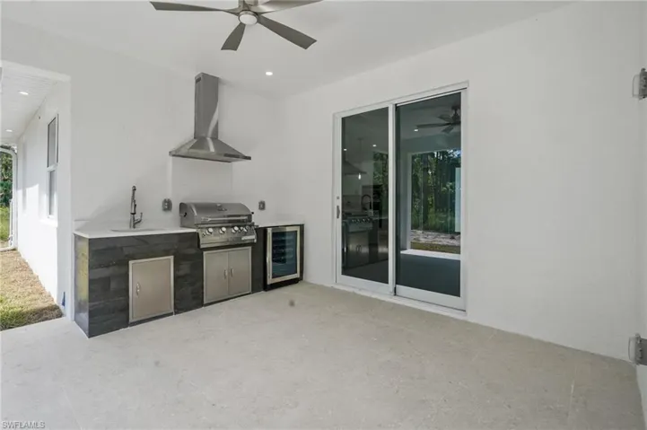 Kitchen featuring wall chimney range hood, wine cooler, ceiling fan, and recessed lighting