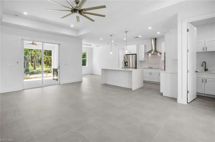 Unfurnished living room featuring a ceiling fan, recessed lighting, a tray ceiling, and light tile patterned flooring