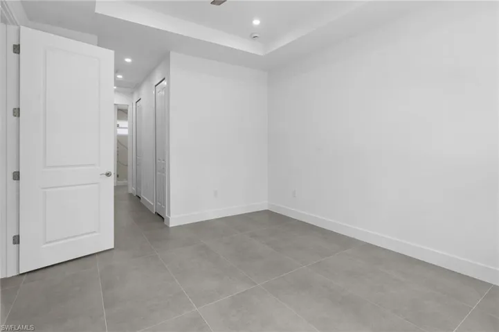 Unfurnished bedroom with light tile patterned floors, recessed lighting, a raised ceiling, and ceiling fan