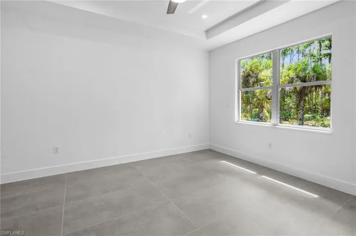 Empty room with a ceiling fan, recessed lighting, light tile patterned flooring, and a raised ceiling