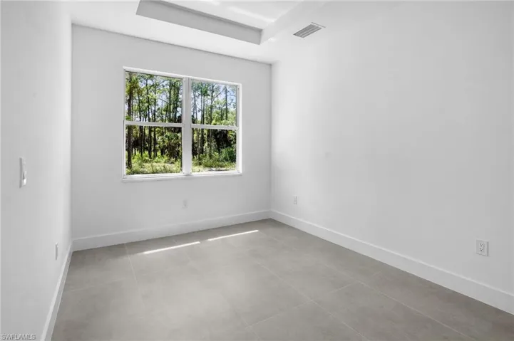 Unfurnished room featuring light tile patterned floors and a tray ceiling