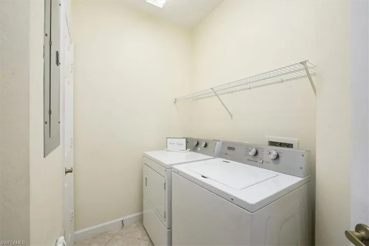 Washroom with washing machine and clothes dryer, light tile patterned flooring, and a skylight