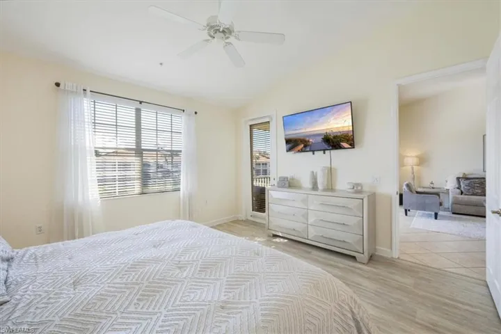 Bedroom with lofted ceiling, light wood-style floors, ceiling fan, and access to exterior