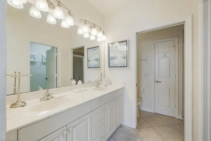 Full bath featuring double vanity, light tile patterned floors, a stall shower, and a closet