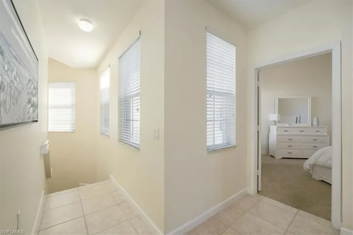 Hallway featuring light tile patterned floors, plenty of natural light, and light carpet