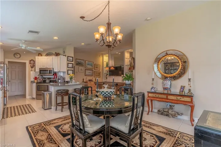 Dining area with light tile flooring and ceiling fan with notable chandelier