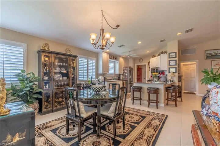 Tiled dining room featuring plenty of natural light, vaulted ceiling, and ceiling fan with notable chandelier