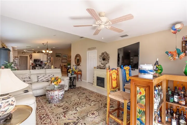 Tiled living room with ceiling fan with notable chandelier