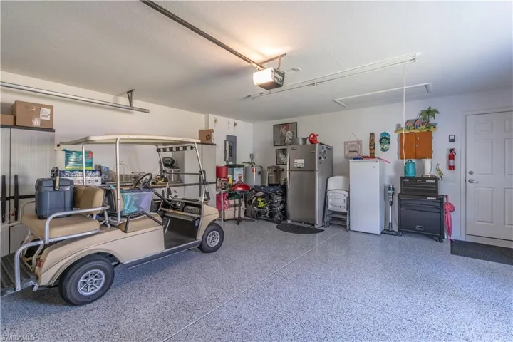 Garage featuring stainless steel fridge, a garage door opener, and white fridge