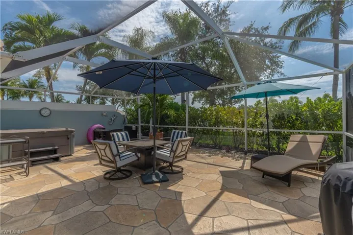 View of patio / terrace with a hot tub and a lanai