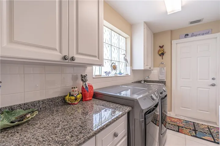 Washroom with washer and clothes dryer, cabinets, and light tile floors