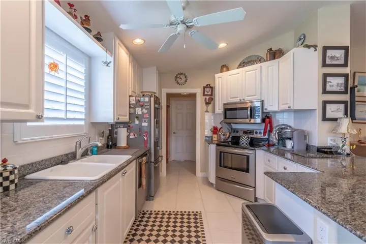 Kitchen with stainless steel appliances, white cabinets, ceiling fan, and backsplash