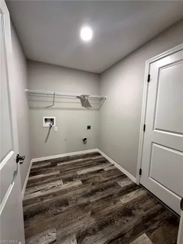 Laundry area featuring wood-finish flooring, light gray walls, a white wire shelf, and an overhead recessed light