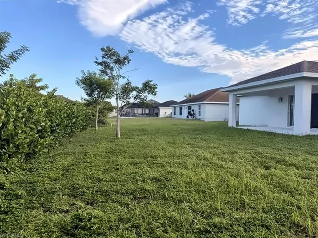 Expansive green space with natural landscaping and partial property exterior