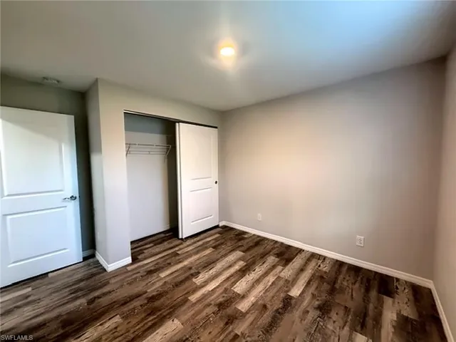 Primary bedroom with wood-finish flooring, white trim, and neutral wall paint