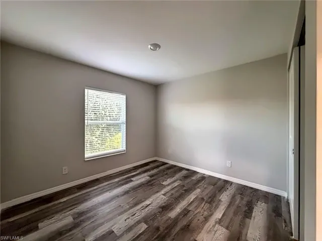 Recessed ceiling light, wood-finish flooring, window with blinds, light-toned wall paint, and white trim