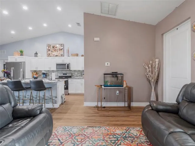 Living room with light wood-type flooring, vaulted ceiling, and recessed lighting