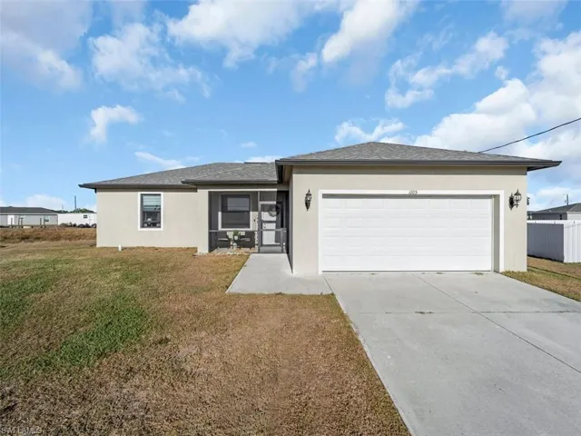 Ranch-style house with stucco siding, concrete driveway, and a front lawn