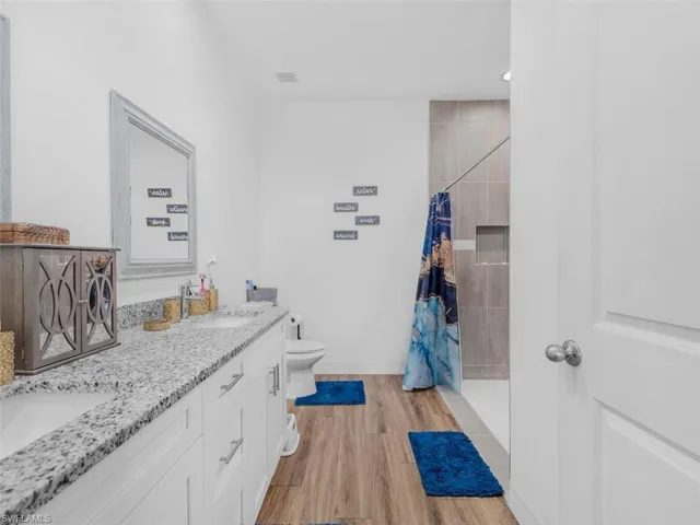 Bathroom with a tile shower, double vanity, and light wood-type flooring
