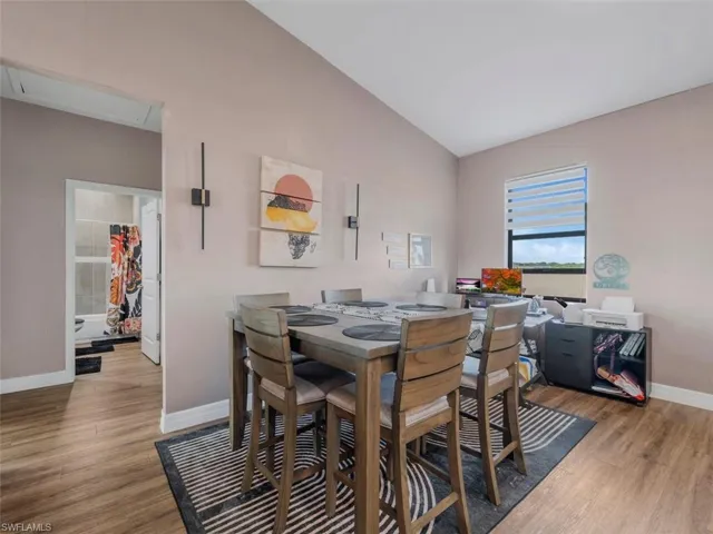 Dining room with vaulted ceiling and light wood-style flooring