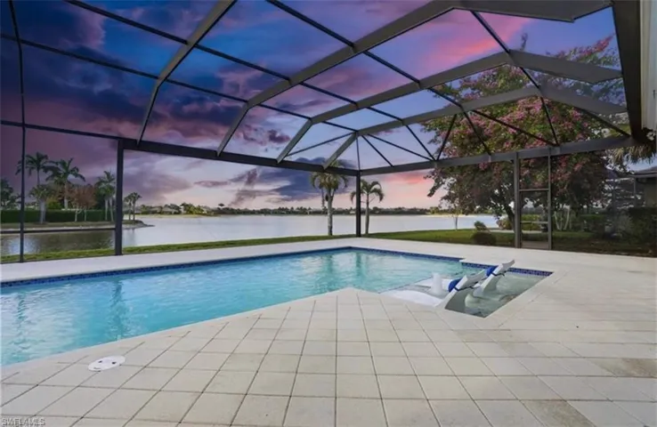 Pool at dusk featuring a water view, a lanai, an outdoor pool, and a sunroom