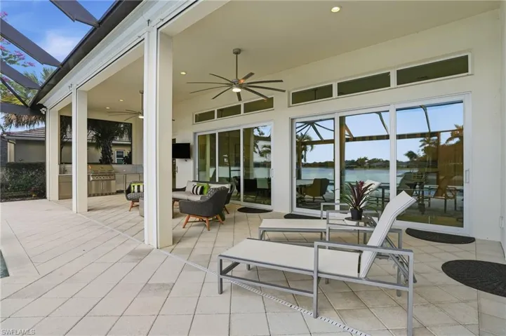 View of patio with ceiling fan, an outdoor kitchen, glass enclosure, and a deck