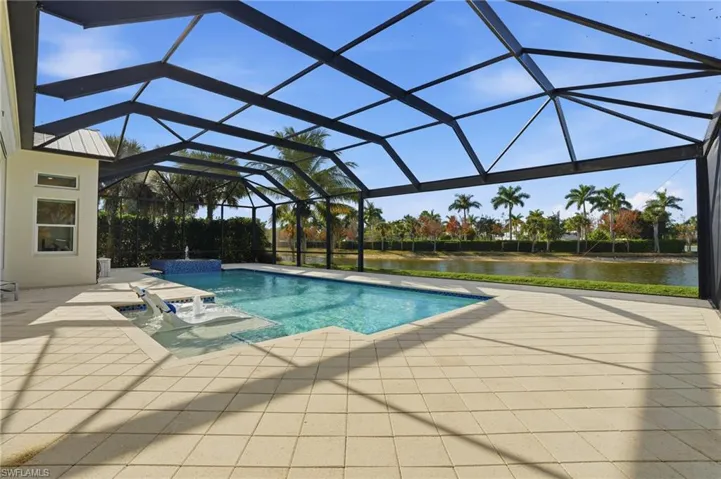 Swimming pool featuring a sunroom, glass enclosure, a patio, and a water view