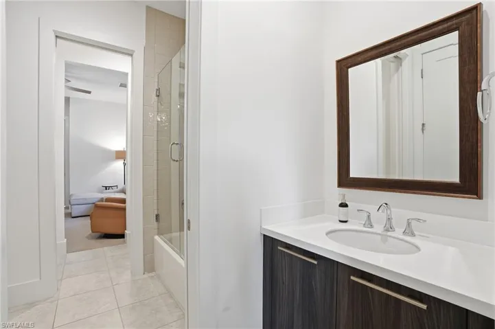 Full bathroom featuring vanity, light tile patterned floors, bath / shower combo with glass door, and a ceiling fan