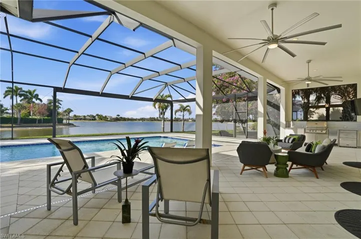 Outdoor pool featuring a patio area, a lanai, a sunroom, an outdoor kitchen, and a water view