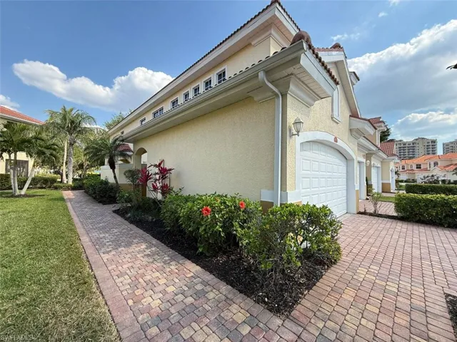 View of property exterior featuring stucco siding, an attached garage, a yard, and decorative driveway