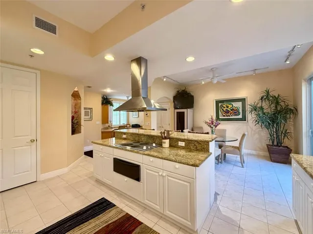 Kitchen with a warming drawer, electric cooktop, island exhaust hood, and a ceiling fan