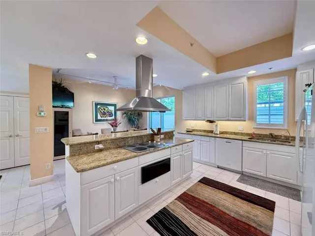 Kitchen with a warming drawer, a healthy amount of sunlight, white appliances, island range hood, and white cabinets