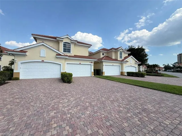 View of front facade featuring stucco siding, an attached garage, a tiled roof, and decorative driveway