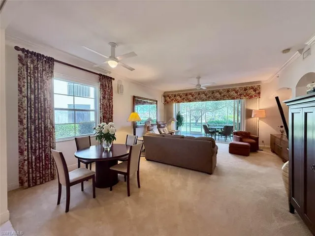 Dining area with a ceiling fan, plenty of natural light, light carpet, and crown molding