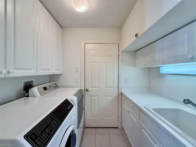 Clothes washing area with light tile patterned floors, a sink, cabinet space, and washer and dryer